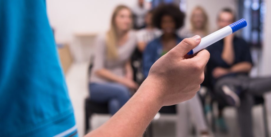 Close up of teacher hand with marker while teaching lessons in school classroom