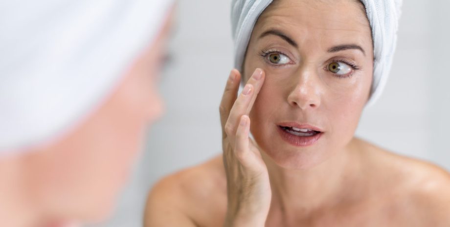 Mature lady looking at her skin in the mirror