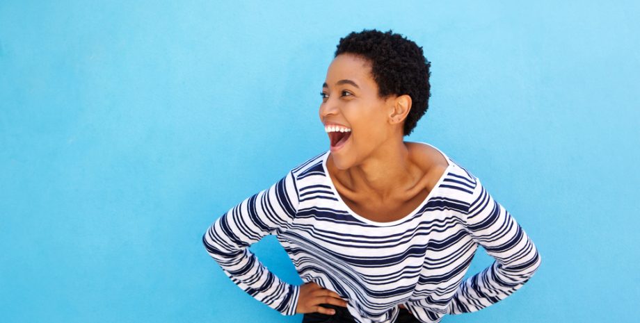 Portrait of happy young woman laughing against blue background