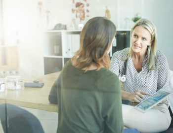 Female doctor showing her patient something on her digital tablet
