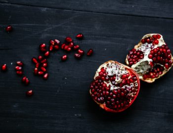 Pomegranate sliced open with loose pomegranate seeds next to it