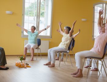 A group sitting in chairs practicing yoga poses.