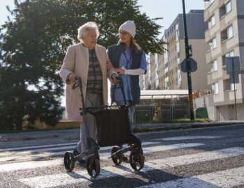 A young woman helping an elderly person across the road.