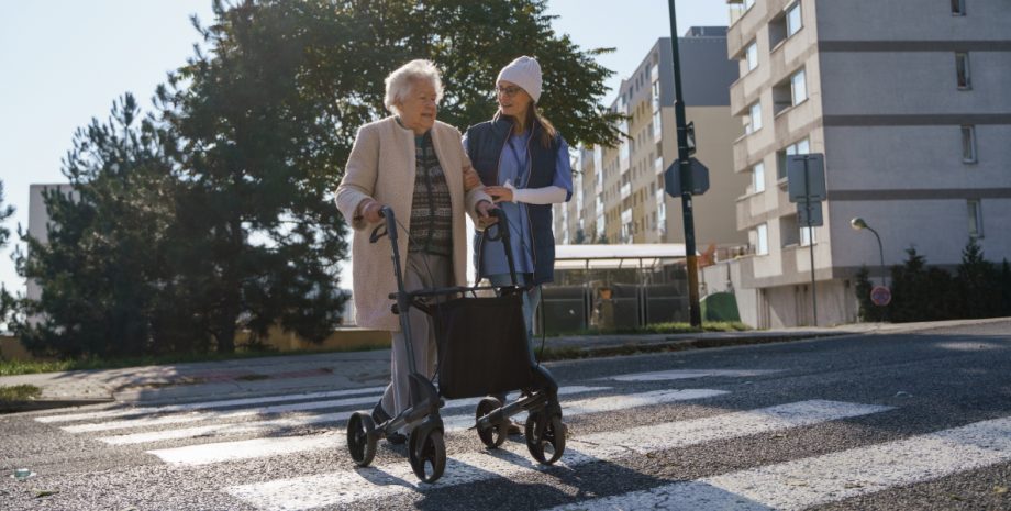 A young woman helping an elderly person across the road.