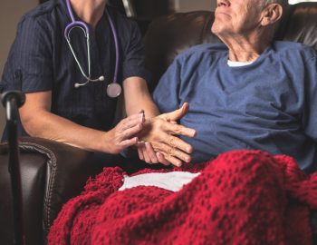 Elder man receiving care from a nurse.