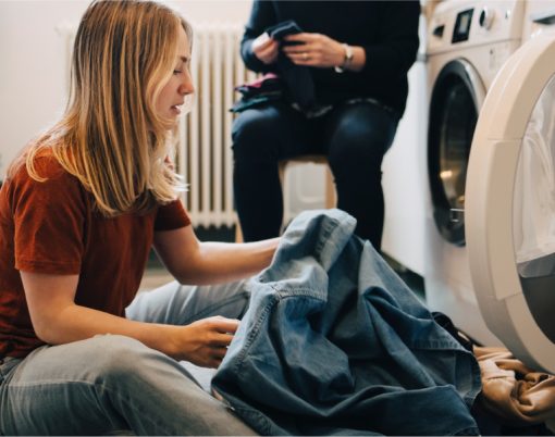 Young woman removing clothes from the washing machine.