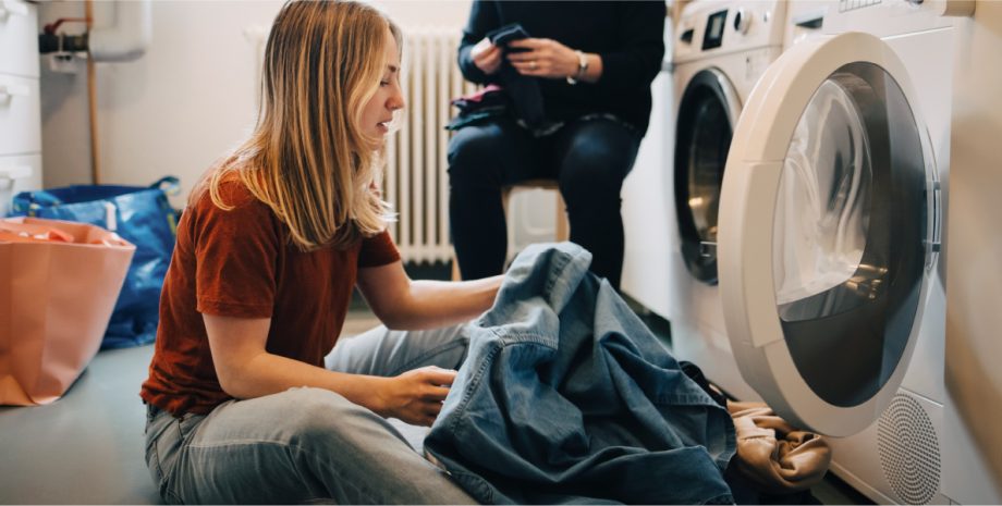 Young woman removing clothes from the washing machine.