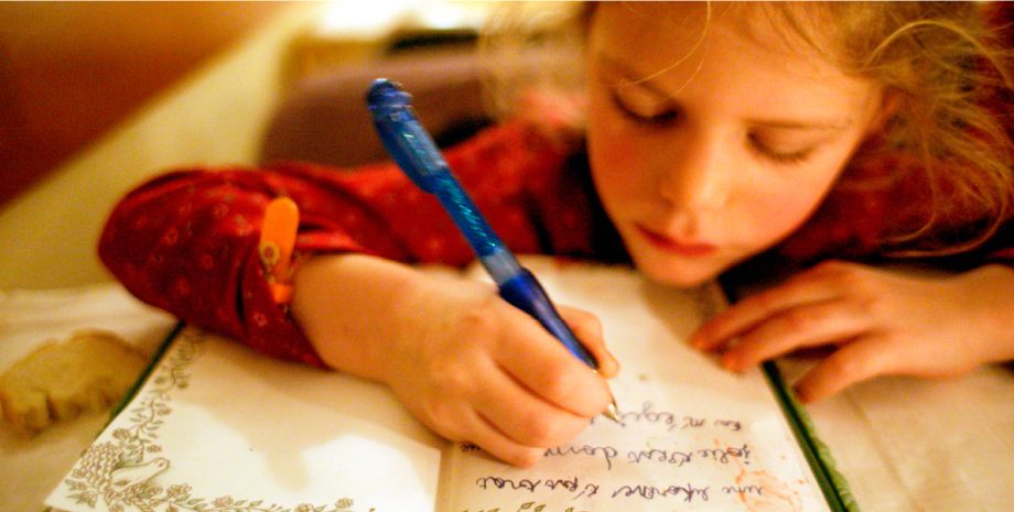 A young girl writing in a journal.
