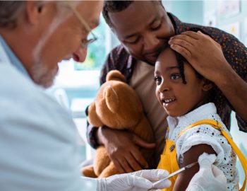 Doctor giving a small girl a shot in the arm.