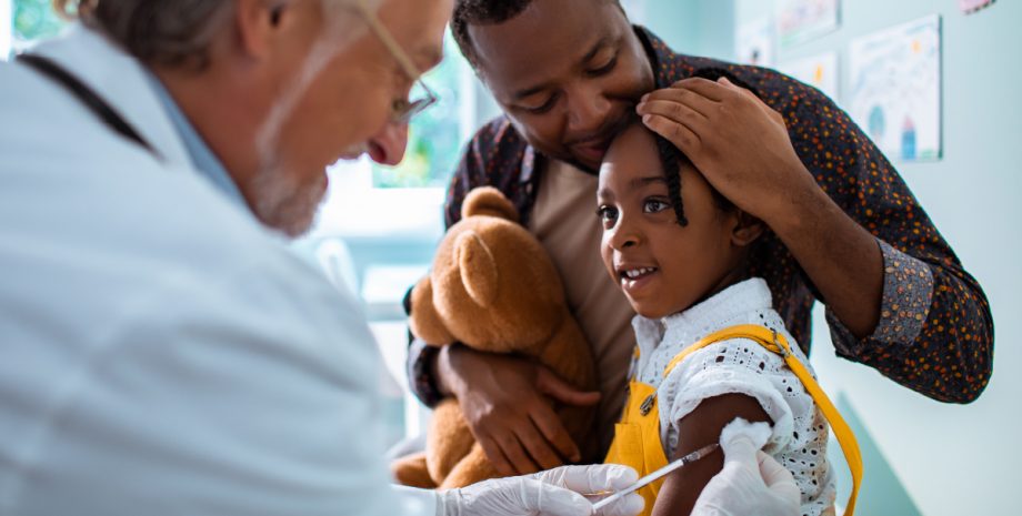 Doctor giving a small girl a shot in the arm.