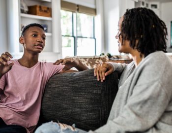 A parent and a child having a discussion on the couch.