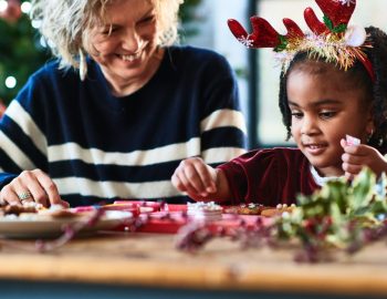 Older woman building holiday crafts with a younger child.