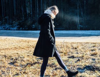 Woman walking alone outside in a heavy coat.