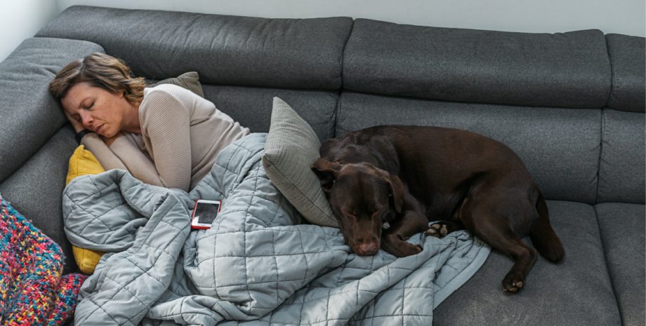 A woman napping with her dog on a couch.