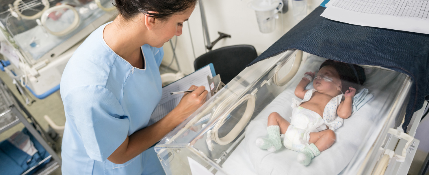 nurse with clipboard checking on a baby in neonatal care