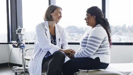 Smiling female doctor talking to woman in hospital