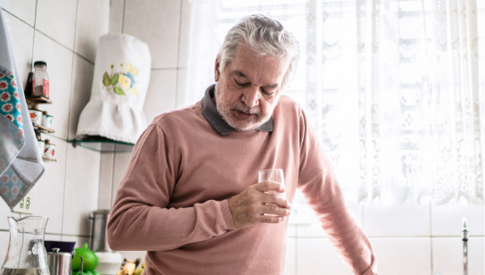 Senior man feeling heartburn and swallowing pain at home
