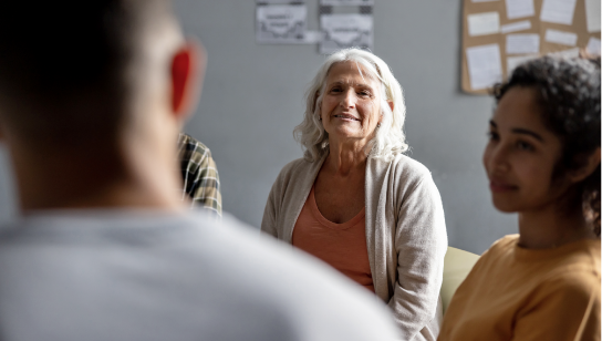 Senior woman listening to a man talking at a group therapy session