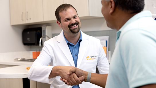 Hancock Health doctor shaking hands with patient in an exam room