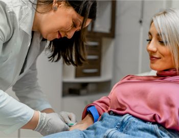 An elderly woman having blood drawn by a doctor.